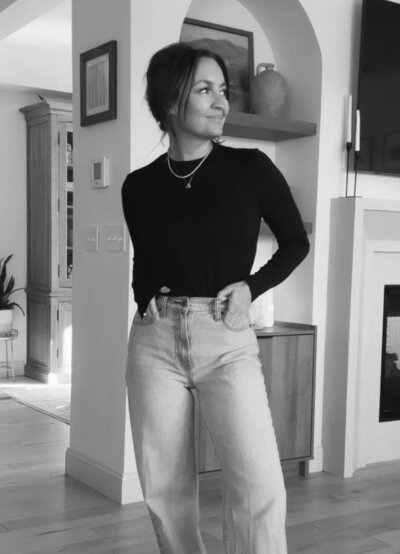Woman wearing black shirt and jeans smiling with hands in pockets