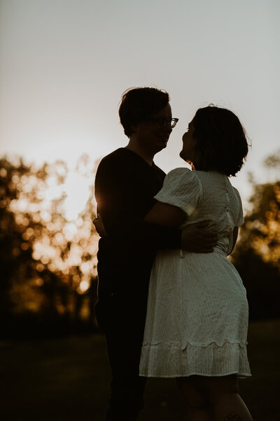 Engaged couple holding each other during sunset at Assiniboine Park