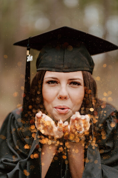 A woman in a graduation cap blowing confetti.