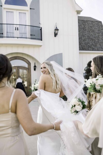 bridesmaids helping bride walk back inside