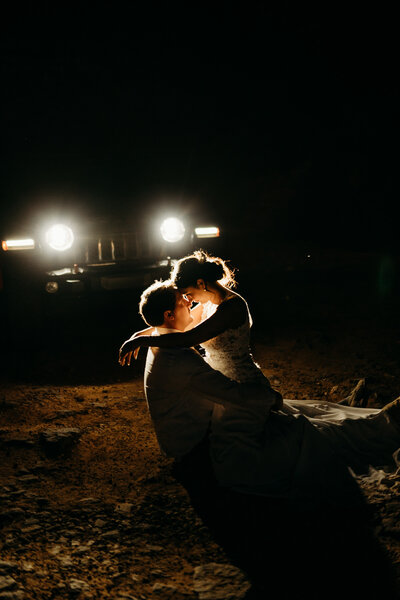 bride and groom cuddling in jeep headlights after eloping at merry go round rock in sedona