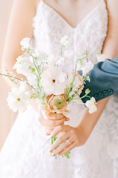 bride holding a beautiful light colored bouquet of flowers with roses and eucalyptus