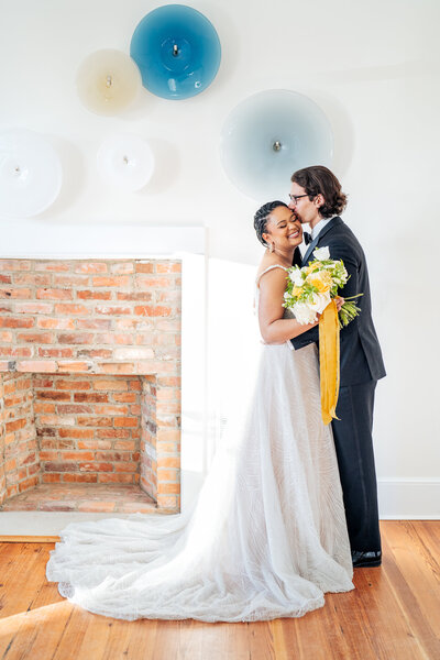 smiling bride and groom in front of fireplace at the Upchurch wedding venue in Cary, NC