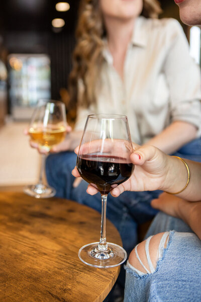 Two glasses of wine being held by a table
