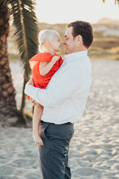 A father and daughter touch noses on the beach near Hotel Del Coronado in San Diego