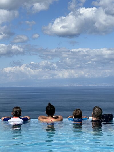 Family overlooking the sea from an infinity pool