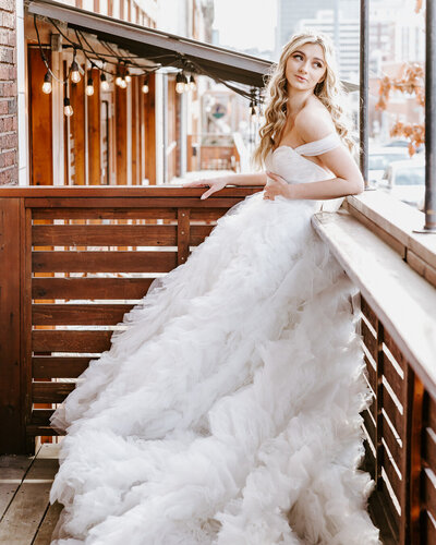 bride leaning on railing looking over shoulder with flowing blonde hair