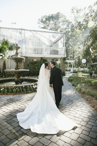 bride and groom walking away at mackey house by fountain
