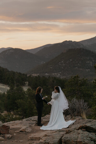 A wedding couple holding hands and saying vows on a mountain overlook 