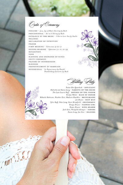 Ceremony program fan with floral detailing, shown in use at outdoor Montana summer wedding.