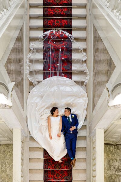 Image from above of a wedding couple laying on a staircase.