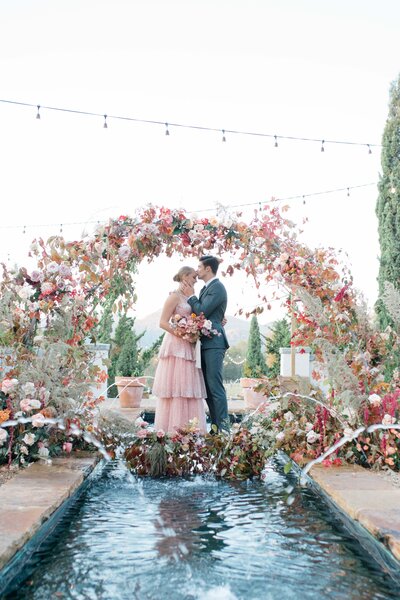 Bride and groom under floral arch in north carolina