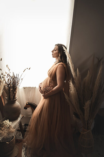 Femme enceinte devant une fenêtre décor bohème
