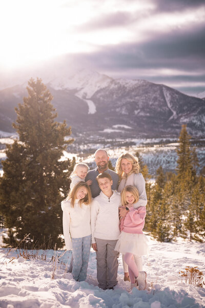Family of 4 standing in front of mountains smiling