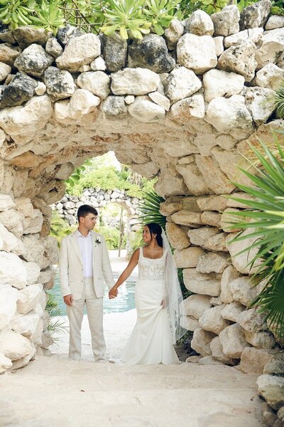 Bride and groom under rock tunnel showing reasons for using a travel agent for destination wedding