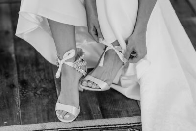 Bride putting on wedding shoes before her first look. Intentional wedding planning and genuine moments. 
