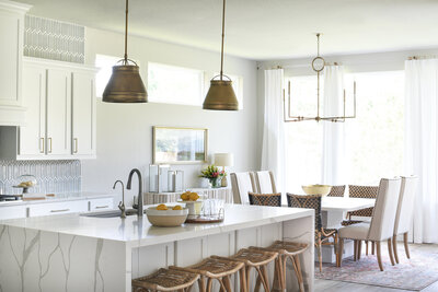 Kitchen island with brass lighting and rattan stools