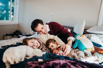 family-of-four-snuggling-in-bed-after-welcoming-second-daughter