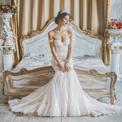 A bride poses on an elegant bed for her bridal session.