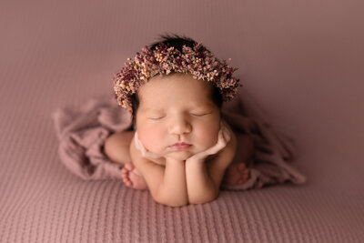 newborn baby girl sleeping posed with a small camera