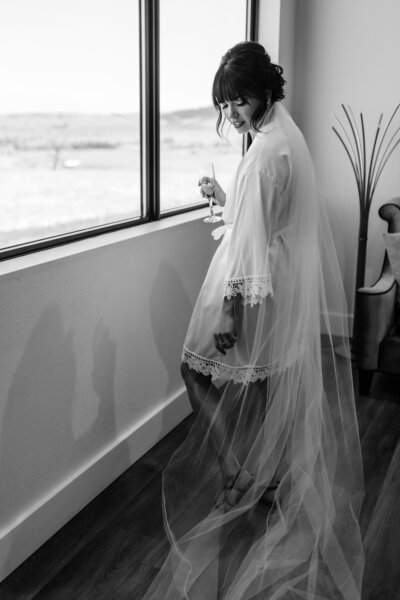 black and white of woman in veil holding champagne