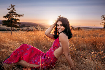 Salem Senior Photography, girl sitting in field at sunset with her hand in her hair