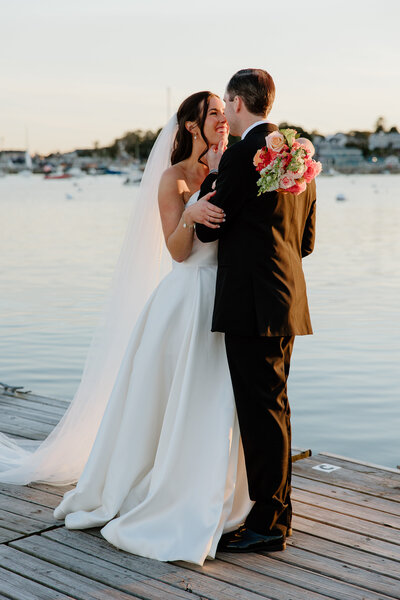 bride and groom embracing during golden hour by the water