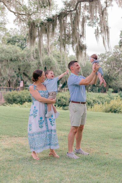Parents lift baby girl in the air during family session for Palmetto Bluff photographer Lamp and Light photography.