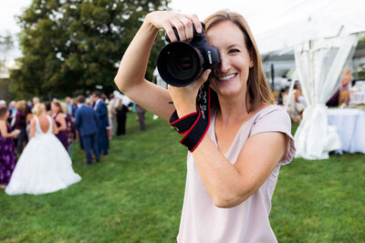 A photographer smiling and holding a camera up to their eye