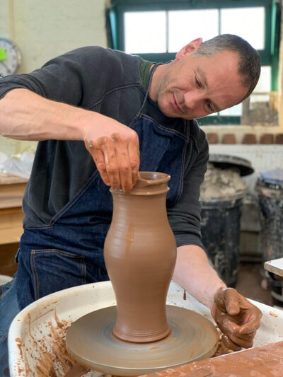 Brian Dickenson professionele pottenbakker en draaier demonstreert aan de draaischijf opbouw van een keramieke pot