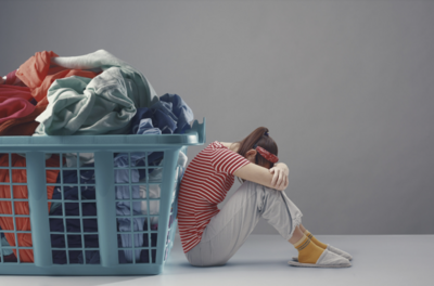 Woman crouched beside a giant full washing basket, representing not knowing where to start when you have ADHD