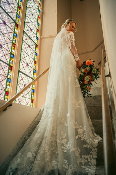 bride walking up stairs with her veil trailing behind her