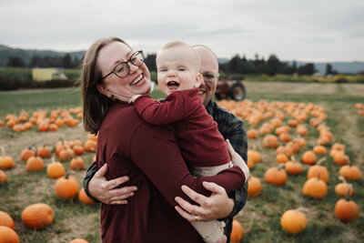 portland lifestyle photographer smiling at the camera at a river with a toddler