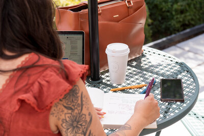 Stephanie, Founder of BCWise Consulting, sitting at a coffee shop writing in a notebook