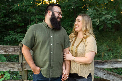 Happy couple holds hands in front of old wooden fence