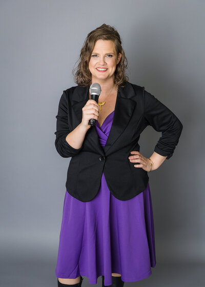 woman in purple dress holding a microphone smiling