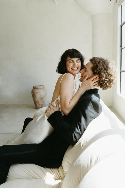 intimate bride and groom on a white leather couch