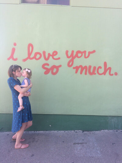Woman holding a child with "I love you so much" behind them.