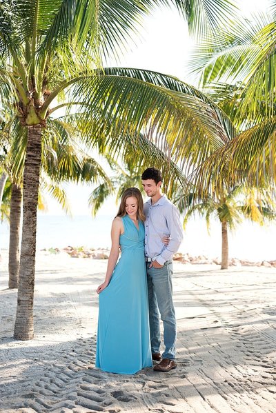 Engagement photos on a private island near Aruba, couple standing on sand with palm trees surrounding them
