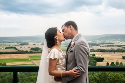 A bride and groom kiss in front of a field