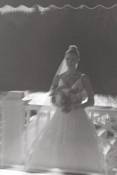 Bride in a v neck wedding dress wearing a top knot standing with floral bouquet