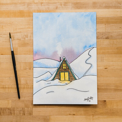 Watercolor painting of an a-frame cabin next to a ski slope by Amy Duffy