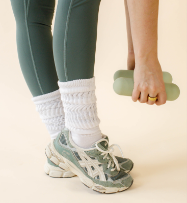 Close up of green sneakers, chunky socks, and green bala hand weights.