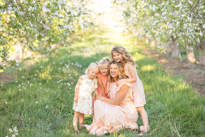 Mom and her 3 daughters sitting in an orchard in Boise during family pictures with Tiffany Hix in Boise