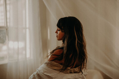 brunette with eyes closed and drapes behind