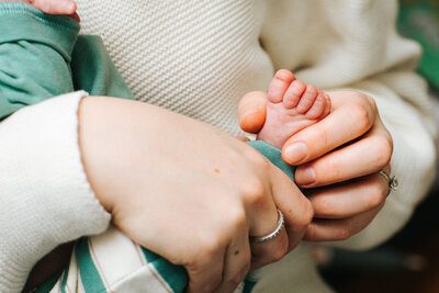 Closeup of newborn baby's foot in the hands of his mother in their Somerville nursery