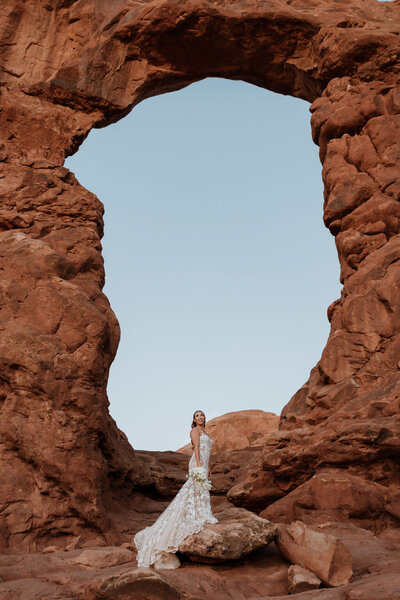 beautiful bride standing un turret arch in moab utah