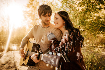 Husband playing guitar while wife hangs off shoulder sharing intimate moment in Minnesota