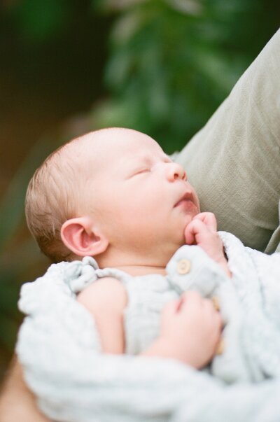 Newborn Portrait taken in home in St Augustine near Jacksonville while baby sleeps in a swaddled blanket in her mother's arms
