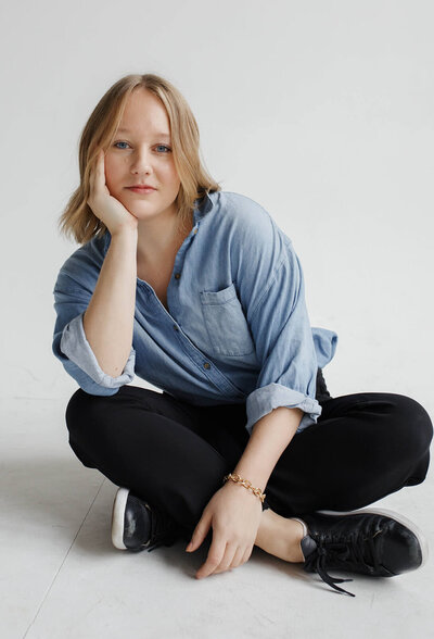 A woman posing for a photo while sitting on the ground 